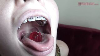 Blue- eyed golden-haired with braces is licking and eating gummy bears in a very hawt way